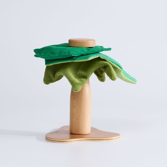 A wooden toy tree with a green plush canopy on a sturdy wooden base