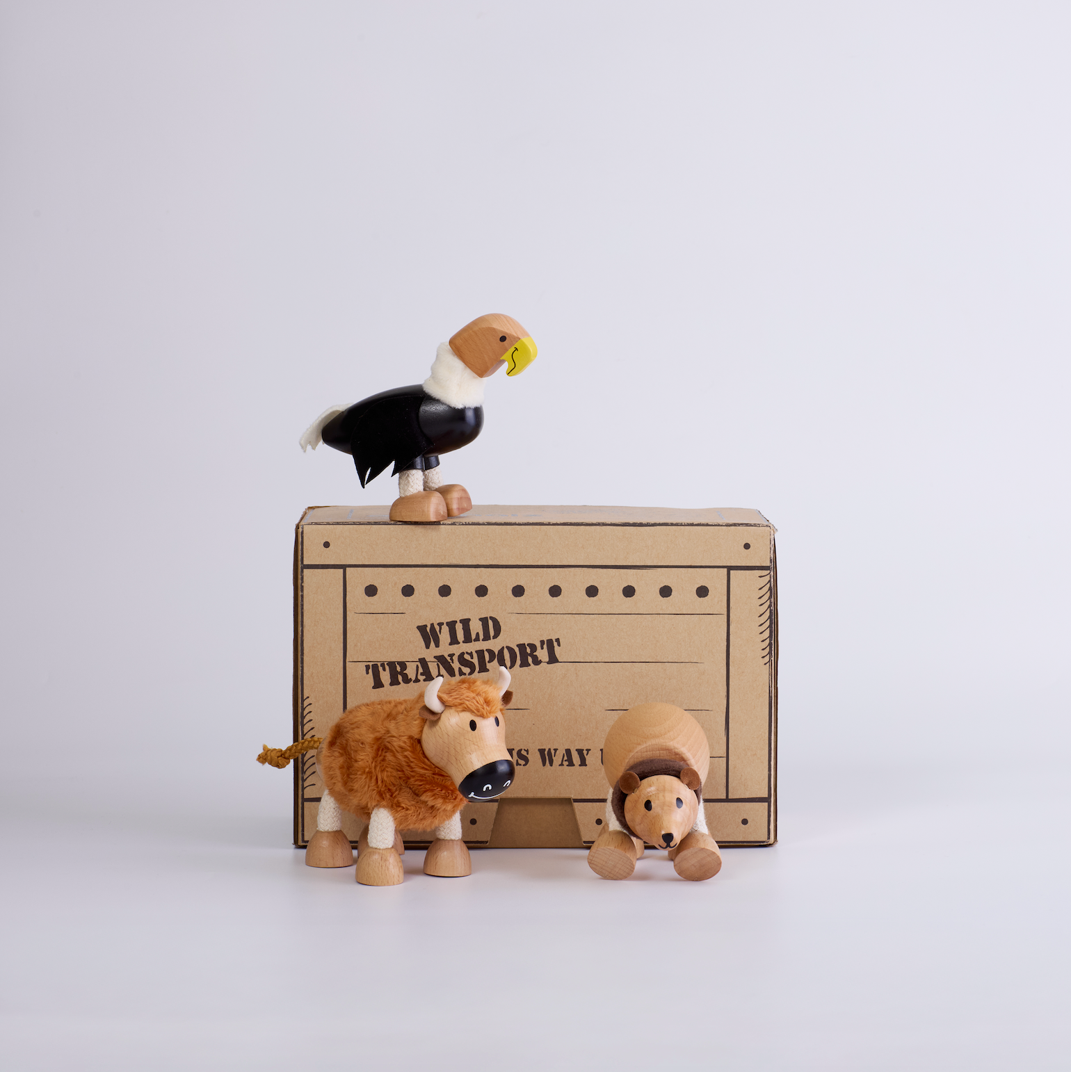 Wooden animal figurines on a cardboard box labeled 'Wild Transport' against a white background