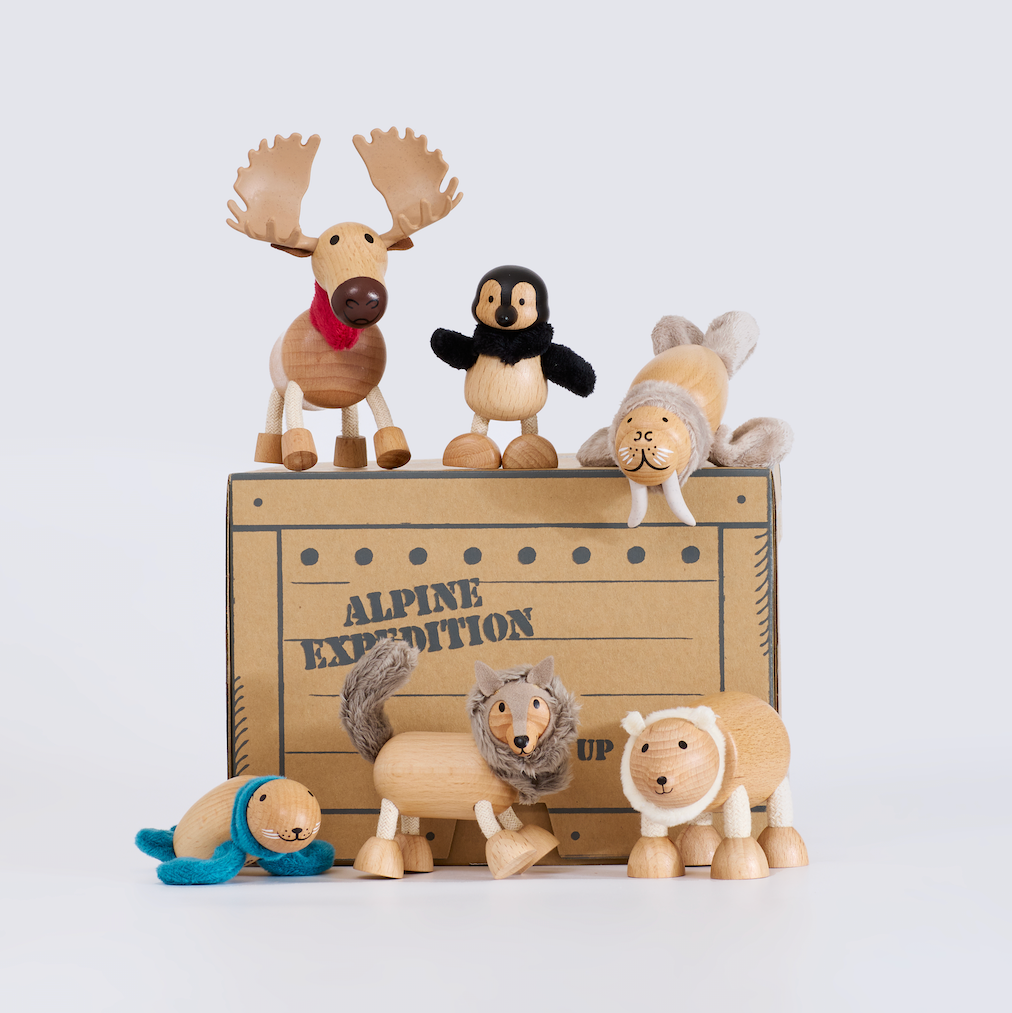 Wooden toy animals on a wooden crate with 'Alpine Expedition' text on a light gray background