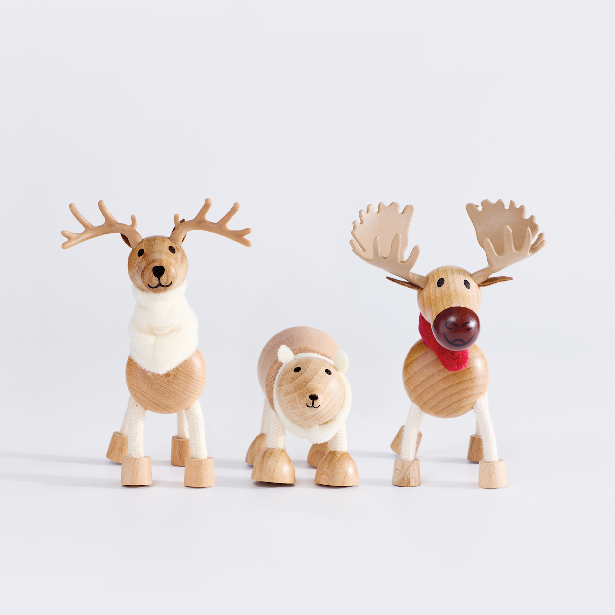 Three wooden reindeer figurines on a light gray background