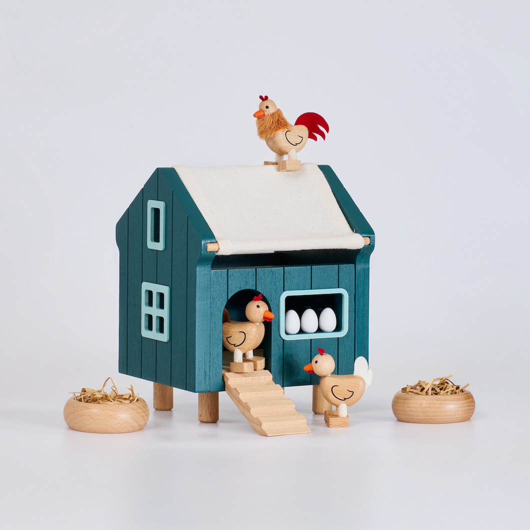 Toy chicken coop with chickens and eggs on a white background
