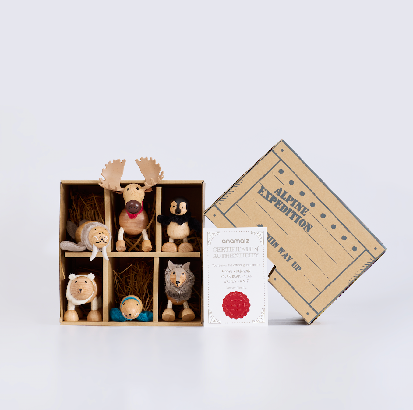 Set of wooden animal figurines in a box with a branded card on a light gray background