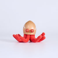 Small wooden toy octopus with red tentacles on a white background