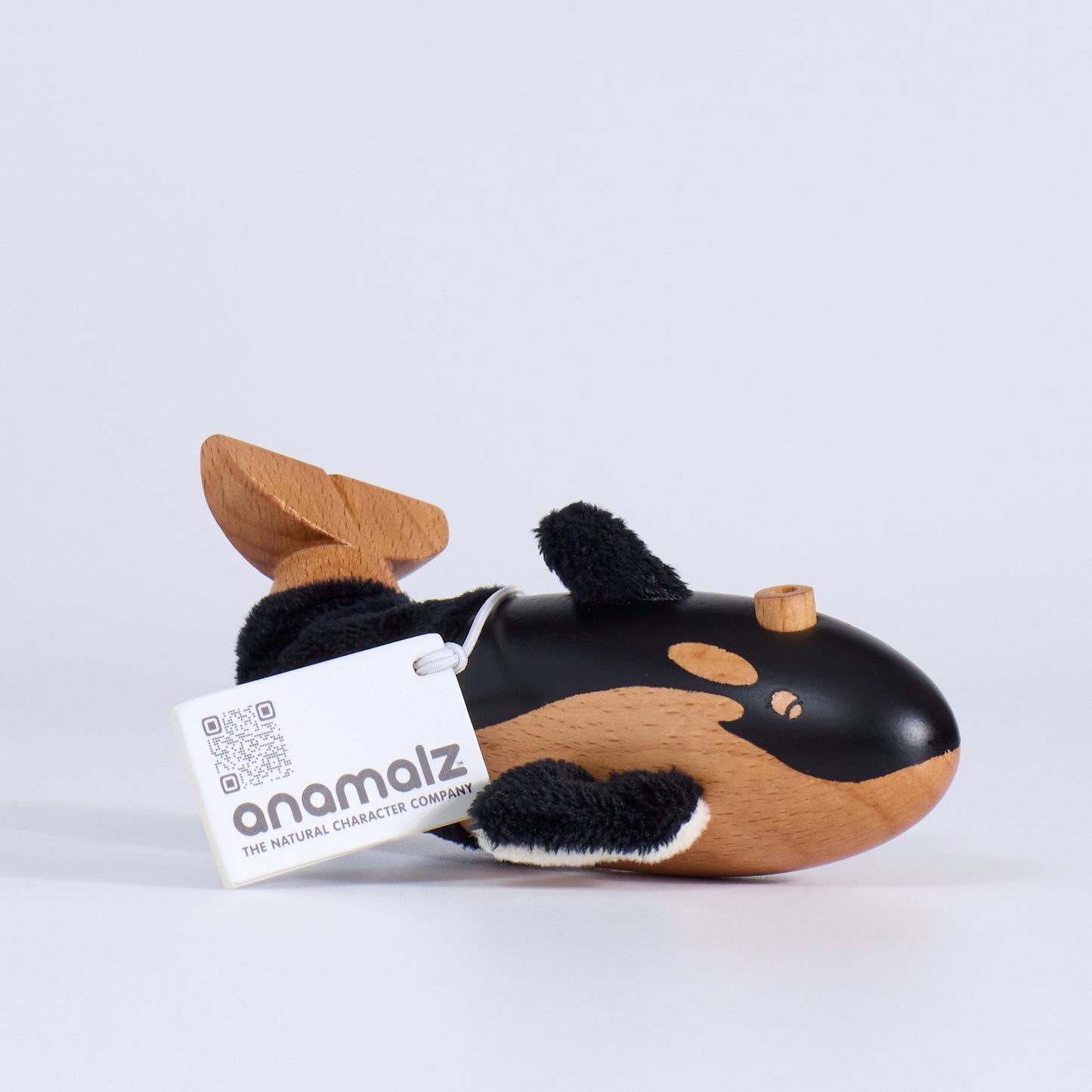 Plush whale toy with a visible brand tag on a white background