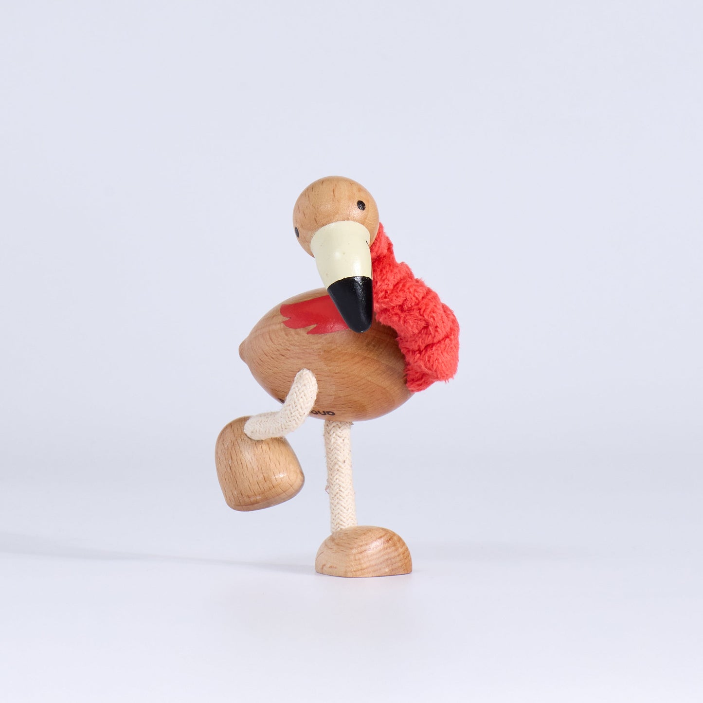Wooden flamingo figurine with a red sweater on a light gray background