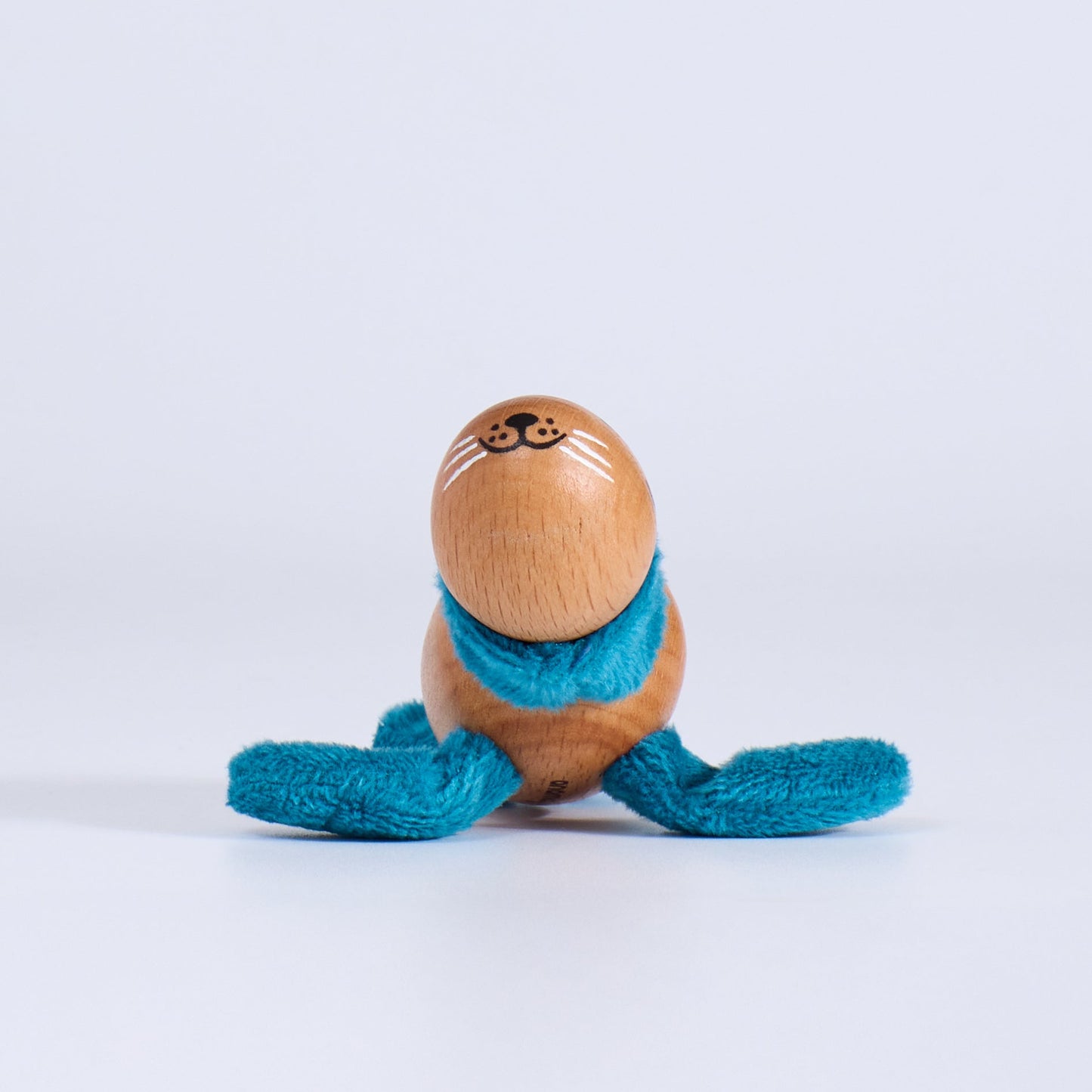 Wooden toy  seal with a blue scarf on a white background