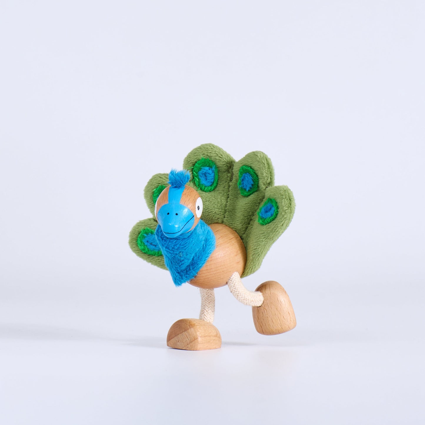 Toy figure of a peacock with a wooden base on a light gray background